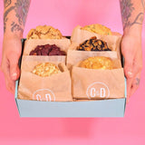 Pick Your Own Cookies box with six assorted chunky New York Cookies from Crumbs & Doilies held against pink background